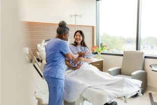 Senior nurse talks to happy new mother