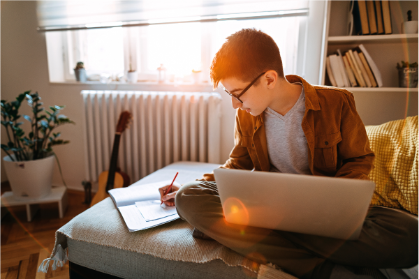 A homeschooler studying for the SAT on his bed