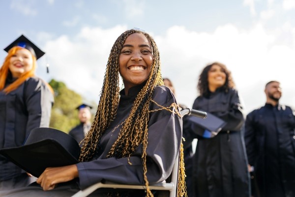 An African American graduate sitting in her wheelchair and smiling.

